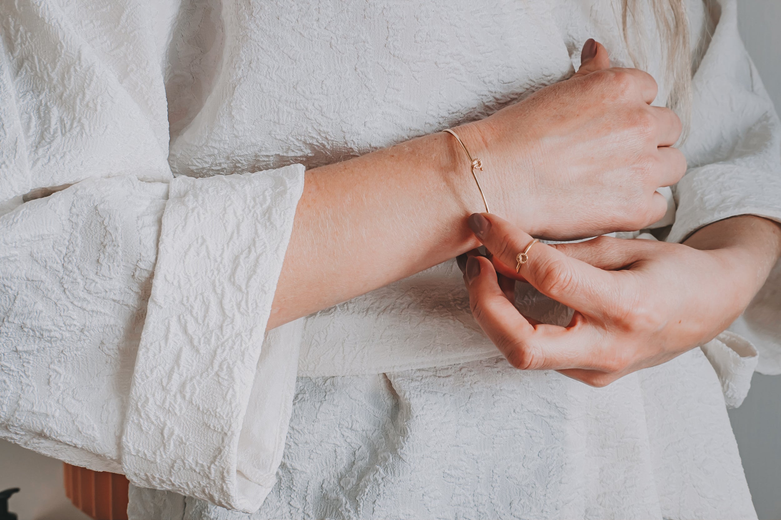 Jag vet inte vem personen är, men bilden visar en person i vit klänning som bär ett elegant armband.