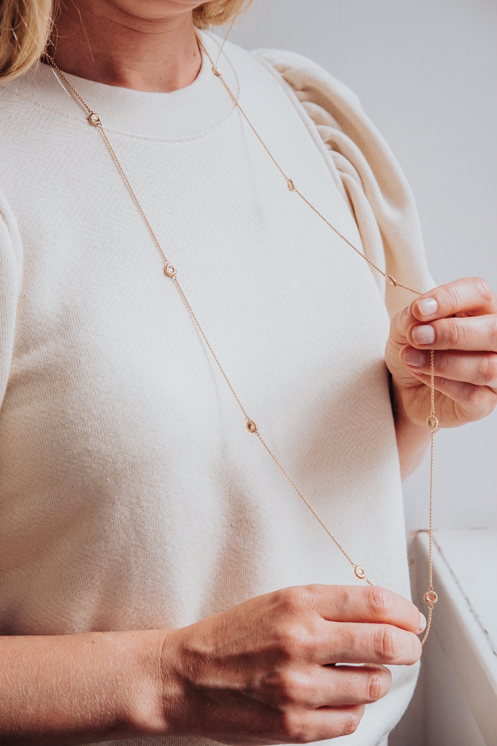 Långt roséguldhalsband med knappkorall på kvinna