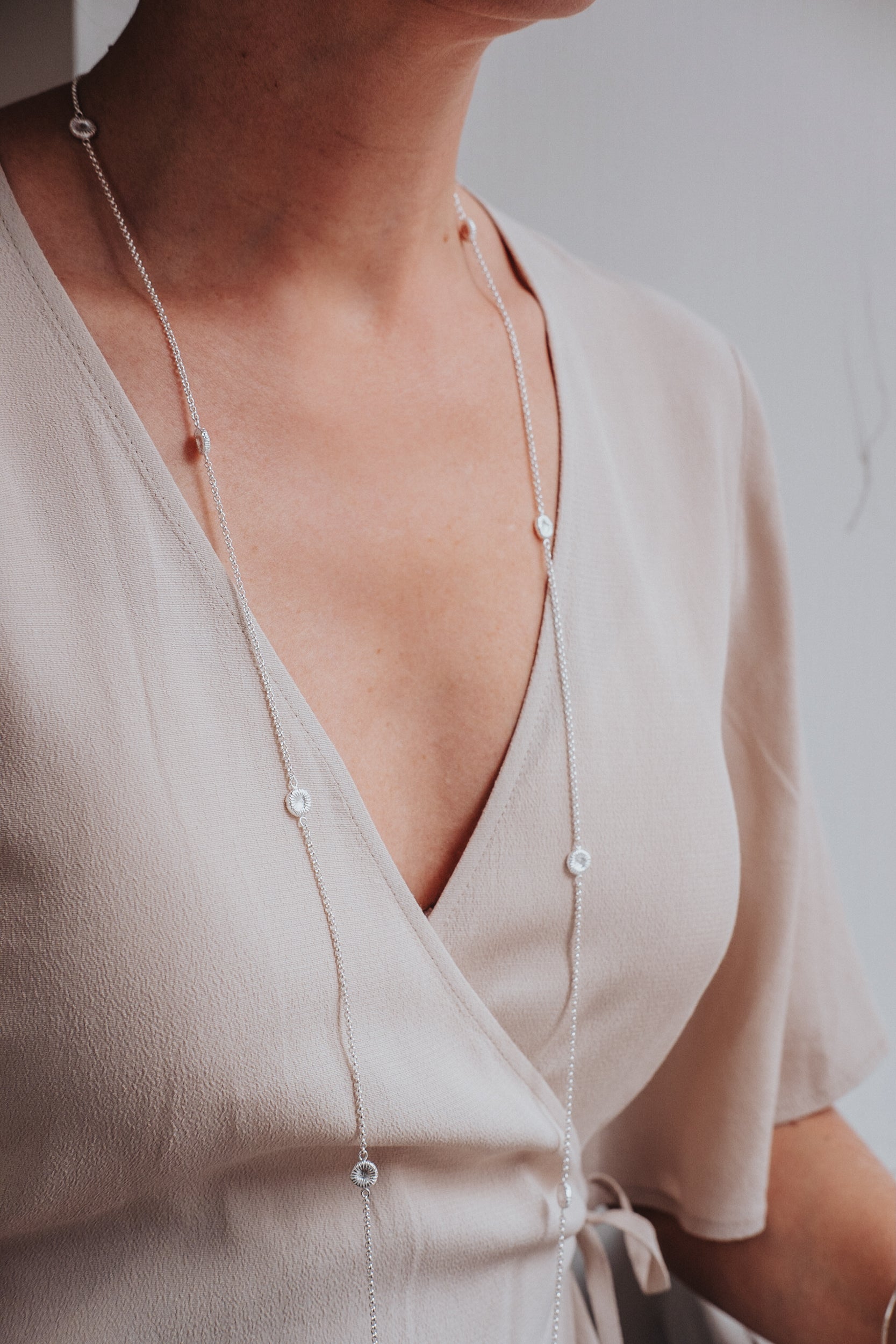 Långt knappkorallhalsband på kvinna i beige klänning